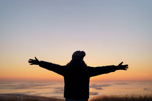 Immagine motivazionale di una donna che alza le mani al tramonto - Foto, immagini