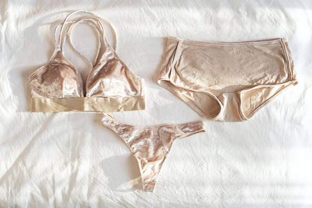 Casual lingerie on white bedsheets. Flat lay with everyday underwear. Beautiful velour bralette and panty.  Shopping and fashion concept. - 写真・画像