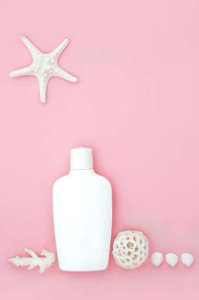 Увлажняющий солнцезащитный крем для загара бутылка лосьон для защиты кожи УФ летом с ракушками на розовом фоне. Естественная и чистая здоровая кожа. Копирование пространства. - Фото, изображение