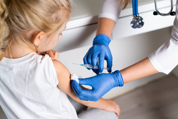 вакцинация детей, маленькая девочка на приеме у врача, инъекция в руку, рожок - Фото, изображение
