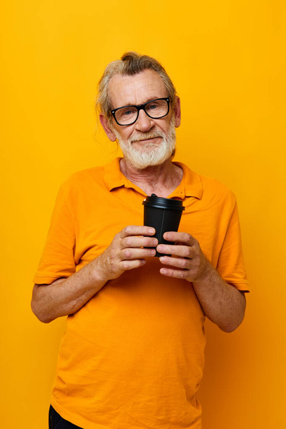 Portrait of happy senior man with black disposable cup isolated background - Photo, image