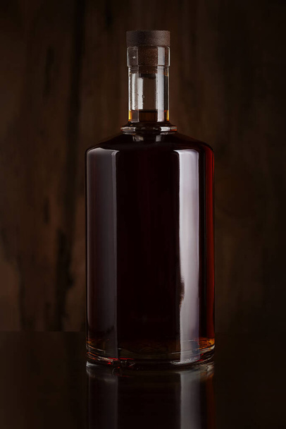 Brandy bottle on a dark background made of old wood - Fotó, kép