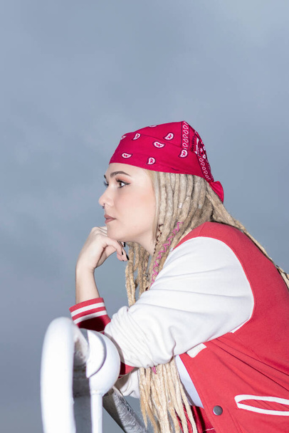 blonde woman with dreadlocks and a red headscarf pensive - Фото, изображение