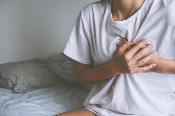 Woman holding chest because of heart disease, heart attack, heart pain or chest pain - Photo, Image