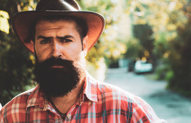 Young handsome man in cowboy hat with long beard, mustache and trendy hairdo. - Foto, Imagen