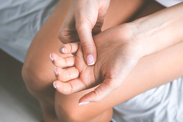 Жінка страждає від болю в руці або болю в пальцях. Оніміння рук або оніміння кінцівок. Масаж болючої руки
 - Фото, зображення
