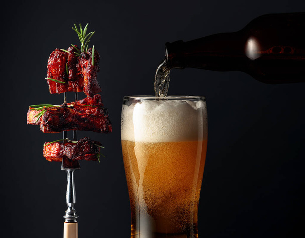 Beer and grilled pork belly with rosemary on a fork. - Foto, Imagem
