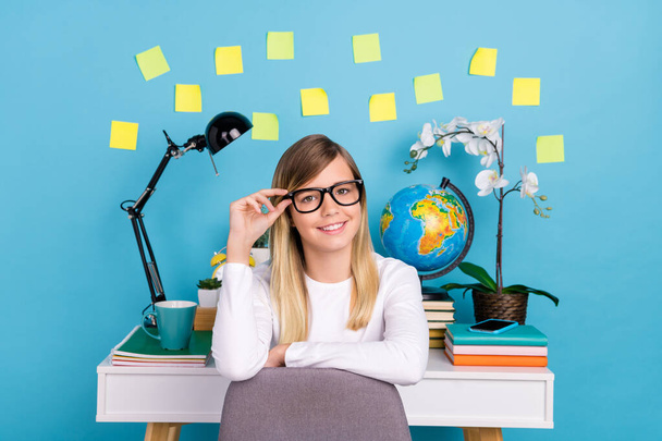 Portrait of attractive cheery intellectual teen girl doing homework touching specs isolated over bright blue color background - Valokuva, kuva