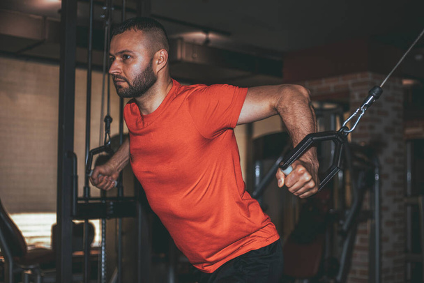 Fit man exercising at the gym on a machine. - Фото, зображення