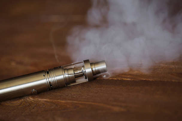 Electronic cigarette on a wooden table. Smoke - 写真・画像