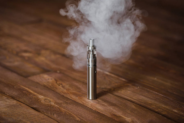 Electronic cigarette on a wooden table. Smoke - Photo, image