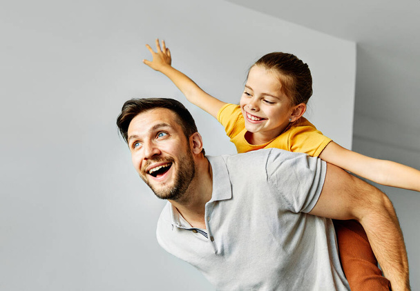 lapsi tytär tyttö perhe onnellinen isä reppuselässä pelaa hauskaa yhdessä tyttö iloinen hymyillen kotiin sisätiloissa liimaus rakkaus - Valokuva, kuva