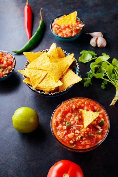 Salsa sauce with ingredients for making. Homemade mexican salsa sauce and tortilla chips on a dark background. Top view - Fotoğraf, Görsel