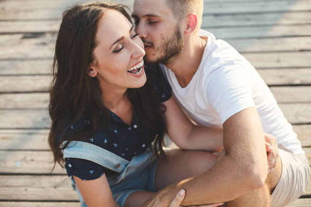 Lovers, guy and girl, close-up laughing against the backdrop of a wooden pier - Foto, afbeelding
