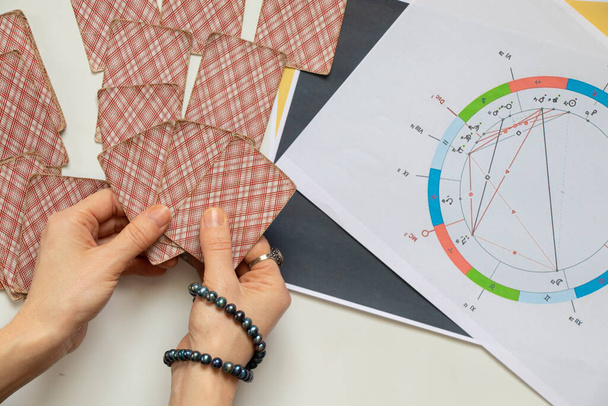 Γενετικοί χάρτες και κάρτες μαντείας στα χέρια ενός κοριτσιού, αστρολογία και μαντεία, αστρολόγος - Φωτογραφία, εικόνα
