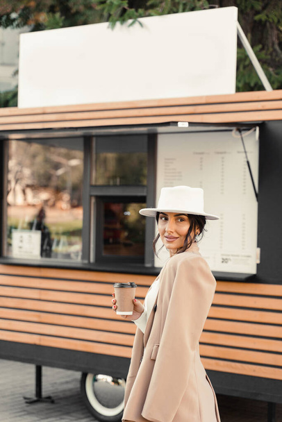 Lächelnde attraktive Frau mit einer Tasse Kaffee in der Nähe des Cafés. Geschäftsfrau macht Pause - Foto, Bild