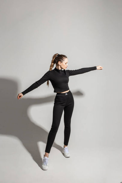 Jeune fille élégante portant des vêtements de sport noirs sur fond de studio gris avec espace de copie. Annonce maquette pour magasin de vêtements - Photo, image
