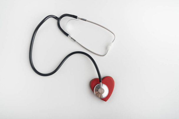 Stethoscope and red heart top view on white background. Health concept. Heart attack - Photo, Image