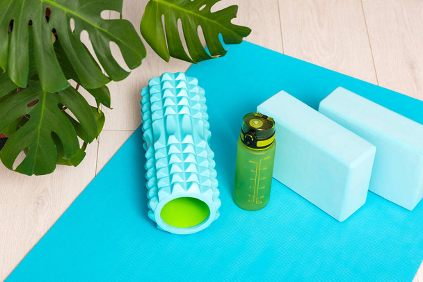 Workout at home. Foam roller for massage of muscle and fascia, gym blocks and a bottle of water. Sport equipment - Photo, Image