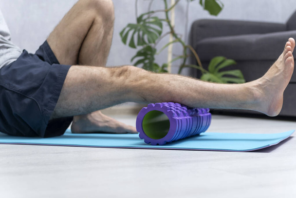Homem usando rolo miofascial de espuma para músculo e fáscia alongamento do pé. Equipamento para MFR. Auto-massagem de pernas - Foto, Imagem