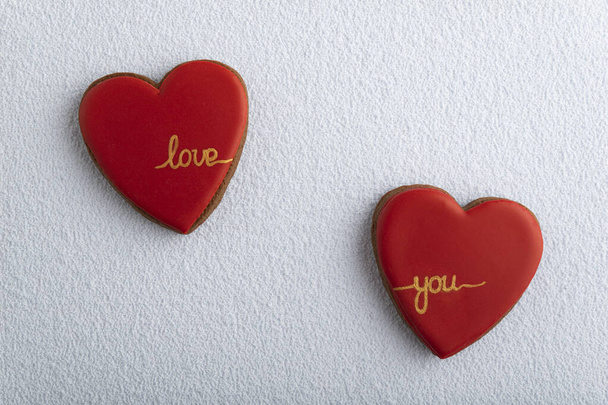 Zwei herzförmige Plätzchen mit roter Zuckerglasur und der Aufschrift LOVE YOU, weißer Hintergrund - Foto, Bild