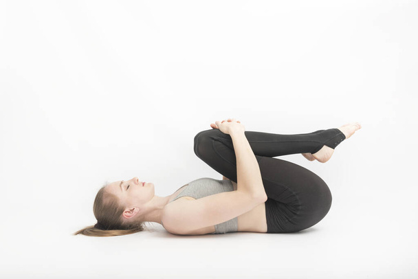 Fiatal nő jógázik térddel a mellkasában. Az ászanák előadásának technikája. meditáció - Fotó, kép