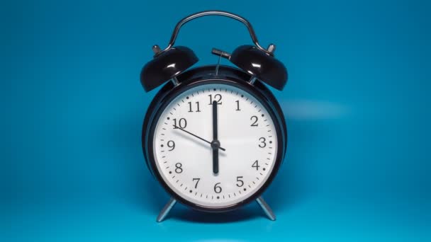 Reloj despertador vintage negro con dos campanas sobre fondo azul - Metraje, vídeo