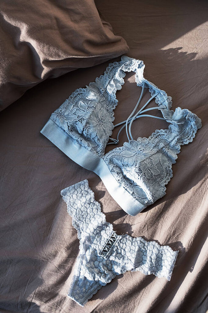 Lace lingerie on grey bedsheets. Flat lay with romantic underwear. Beautiful lace bralette and panty.  Shopping and fashion concept. - Photo, Image
