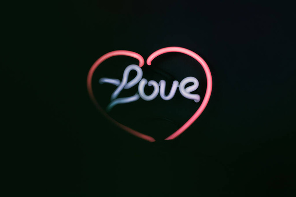 Neon heart shaped lamp with the word love. Dark background with copy space. - Foto, Bild
