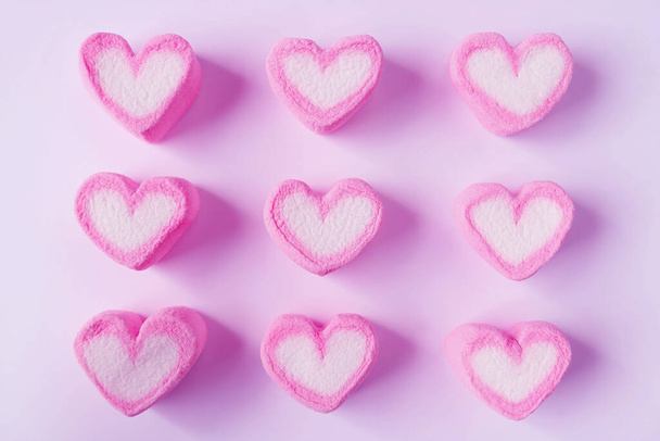 Rijen van roze en wit hart gevormd Marshmallow snoepjes op roze achtergrond - Foto, afbeelding
