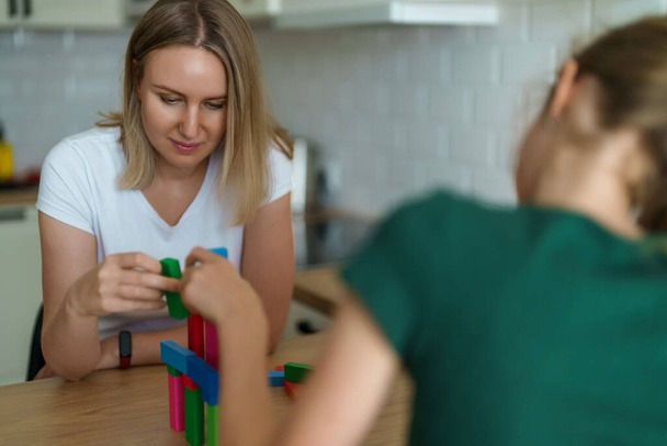Woman and daughter playing jenga tower game at home. - Foto, afbeelding