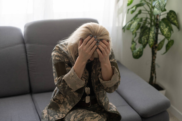 deprimida mulher solitária em uniforme militar em casa
 - Foto, Imagem