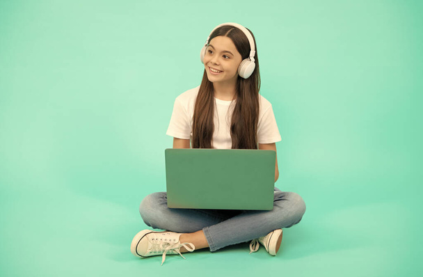 szczęśliwy dziecko dziewczyna używać bezprzewodowego laptopa do rozmowy wideo lub słuchać webinar w słuchawkach, powrót do szkoły - Zdjęcie, obraz