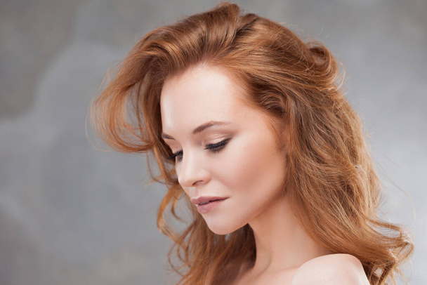A young red-haired woman enjoys the beauty of her hair, - Foto, immagini