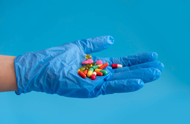 multicolored tablets lie on the doctors hand, the hand is in a medical glove. layout with copy space - Photo, Image
