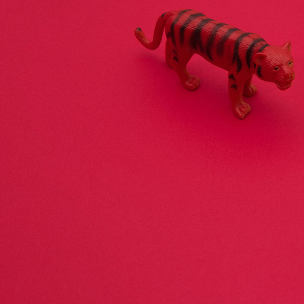 Tiger on a red background wallpaper with copy space. Minimaistic aesthetic scene. - Foto, Imagen