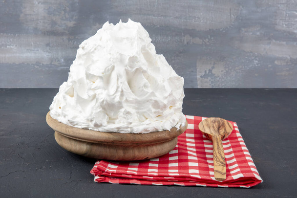 Jauhettu kerma (Powder Cream) kermavaahto lautasella puulattialla. Keittäminen voita kerma keittiössä - Valokuva, kuva