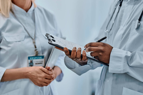 Ausgeschnittenes Bild von zwei Ärzten, die Informationen auf Formularen schreiben. Hintergrund. - Foto, Bild