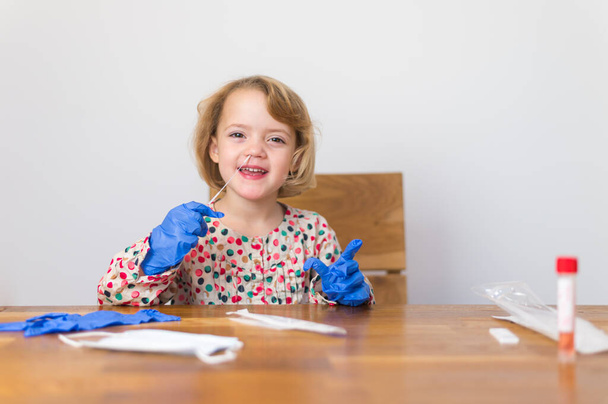 Χαριτωμένο ξανθό κορίτσι αυτο-δοκιμή για τον ιό της κορώνας και περιμένει για αποτελέσματα. - Φωτογραφία, εικόνα