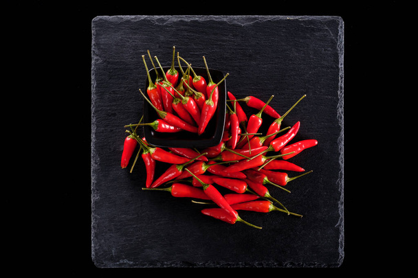kulhollinen punaista chiliä mustalla pohjalla - Valokuva, kuva