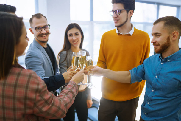 Clinking glasses with champagne. Happy coworkers celebrating their business achievement on a party in the office. Partners celebrating their victory.  - Foto, Imagen