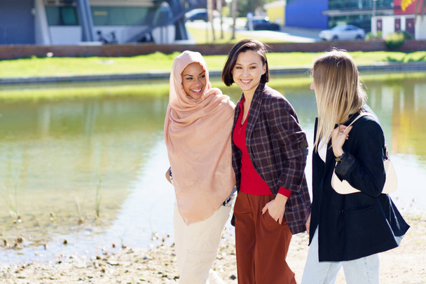 Вміст молодих багатонаціональних жінок, які розмовляють під час прогулянки по набережній в місті
 - Фото, зображення