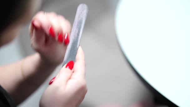 Chica corrige las uñas después de la manicura con una lima de uñas. - Metraje, vídeo