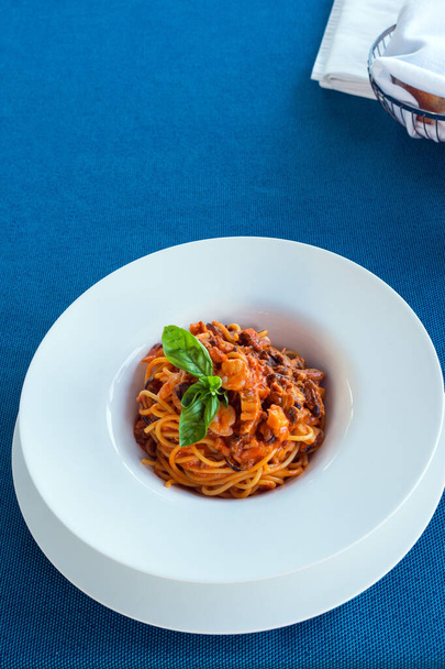 Delicious Italian pasta with seafood in tomato sauce in a white plate. Delicious dinner at the restaurant. A dish of Mediterranean cuisine.  - Valokuva, kuva