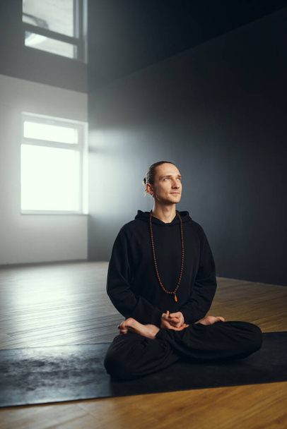 The yogi man sits in the padmasana with buddha mudra. Yoga practice in the studio. - Foto, Bild