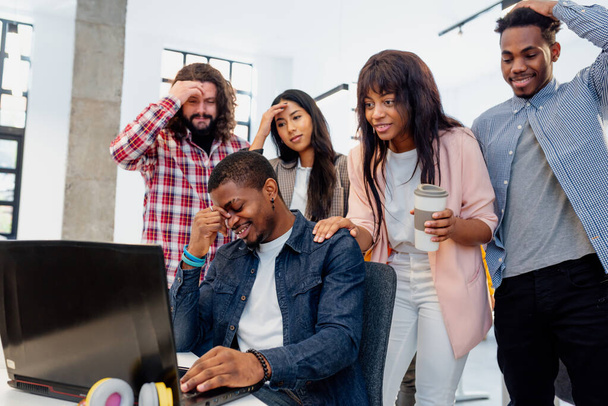 multiracial group of workers looking and working with a laptop lamenting for a bad result. people failing a bet. - Foto, Imagem