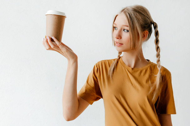 Девушка позирует с кофе на вынос. Пейте ради энергии и удовольствия - Фото, изображение