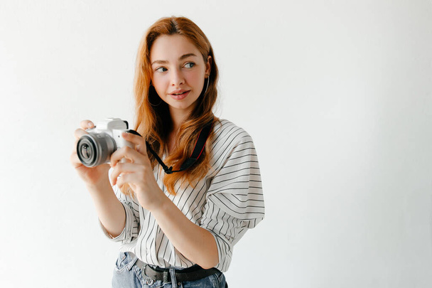 Redheadの女性写真家は、ライトスタジオでカメラで画像を撮影しています。趣味の概念 - 写真・画像