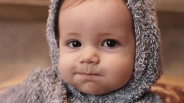 Close view van een baby jongen eten in pyjama, op zoek naar camera - Video