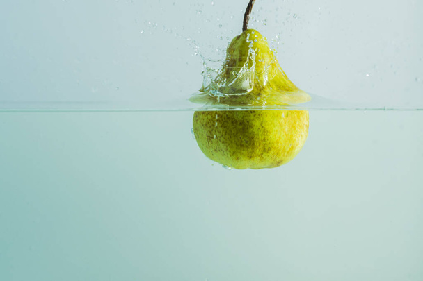Close up view of pear falling in water on background. Gorgeous backgrounds. - Photo, Image